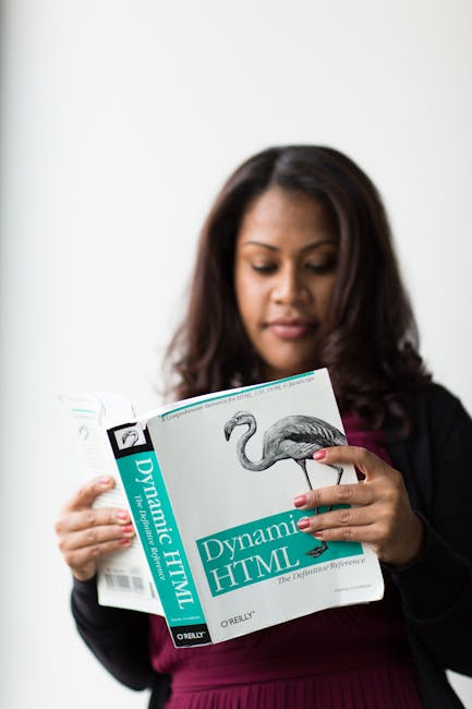 A woman with long dark hair, wearing a black blazer and a maroon dress, is holding and reading a gardening book titled 'Dynamic HTML' published by O'Reilly. The background is plain white, focusing on 